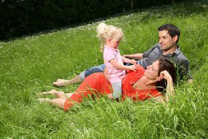Družina sedi na travniku, kjer je velika možnost za klopne bolezni.